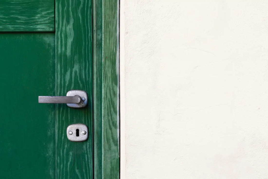 Green door with metal handle against white wall